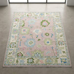 Overhead view of a light pink Oushak rug highlighting pattern integrity and luxurious weave with natural lighting.