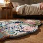 Perspective shot of a corner of the hand tufted floral wool rug, emphasizing edge finish and micro-texture in a cozy bedroom.