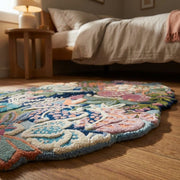 Perspective shot of a corner of the hand tufted floral wool rug, emphasizing edge finish and micro-texture in a cozy bedroom.